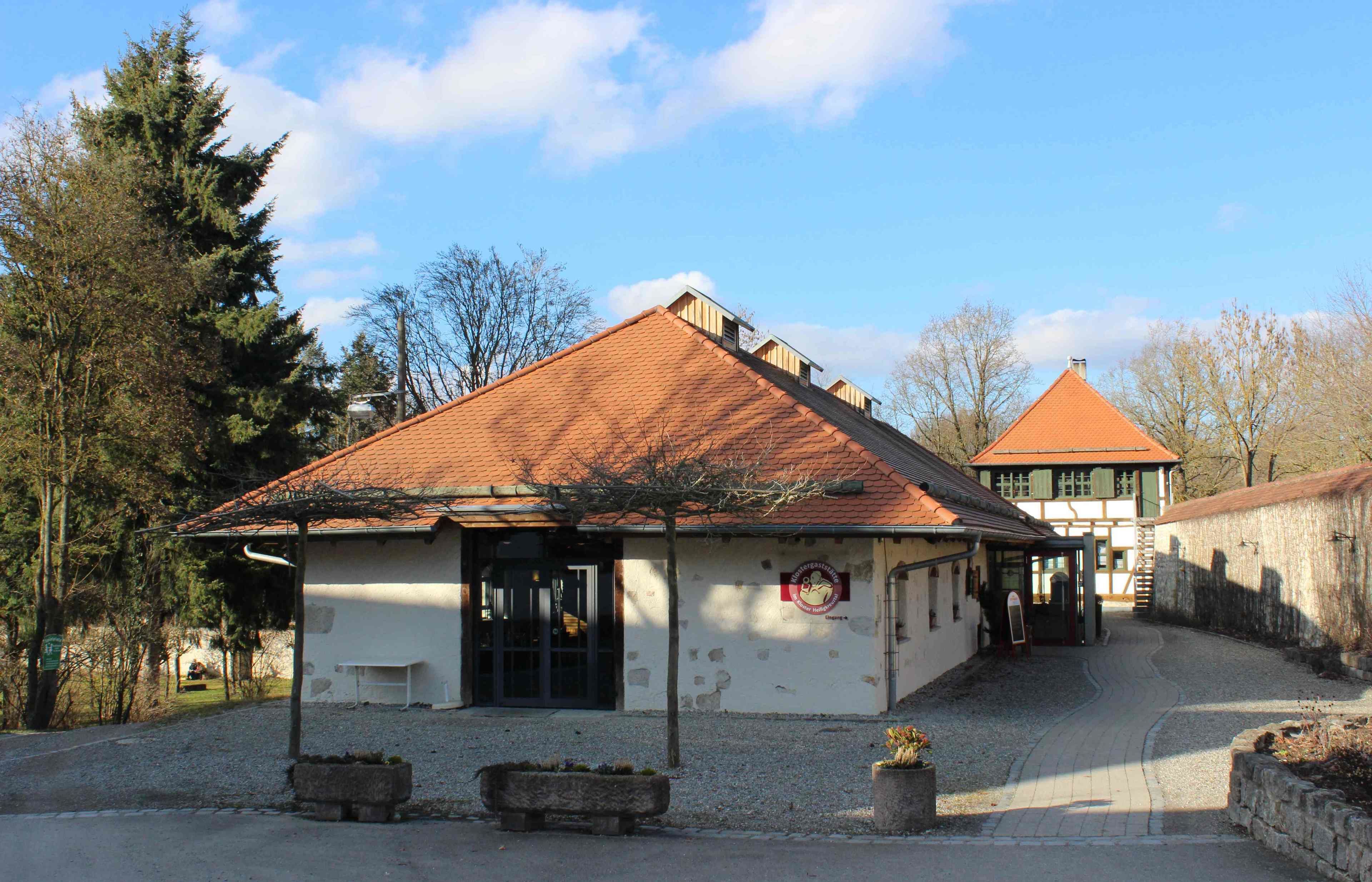 A building with a tiled roof, a small porch, and a sign with a logo.
