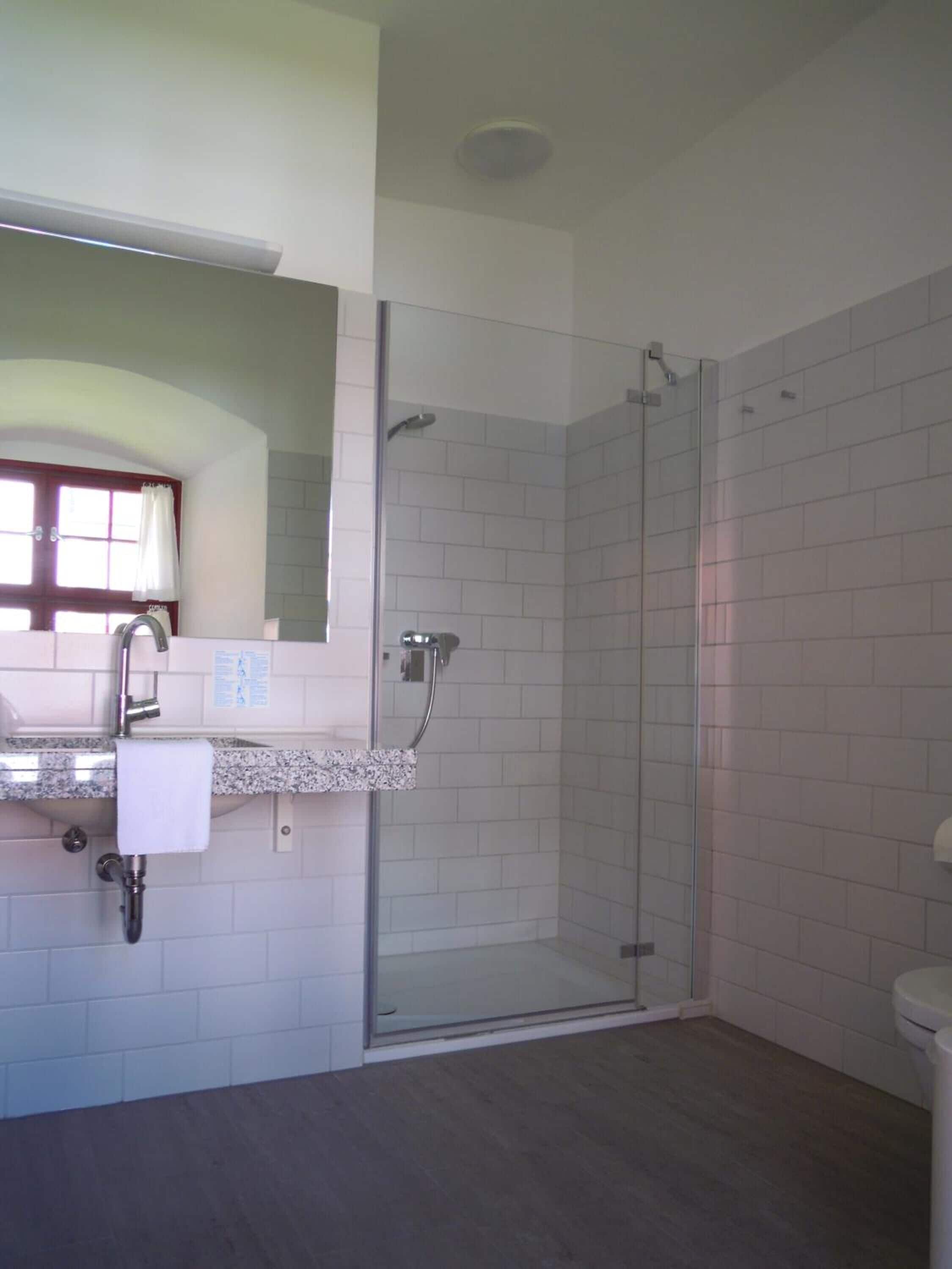 A modern bathroom with a glass shower enclosure, a sink with a marble countertop, and a toilet.
