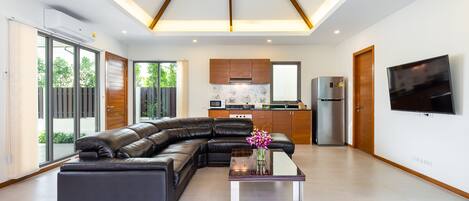 A modern living room with a sectional sofa, a glass coffee table, and a ceiling fan.