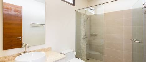 A modern bathroom with a large mirror, a sink, a toilet, and a glass-enclosed shower area.