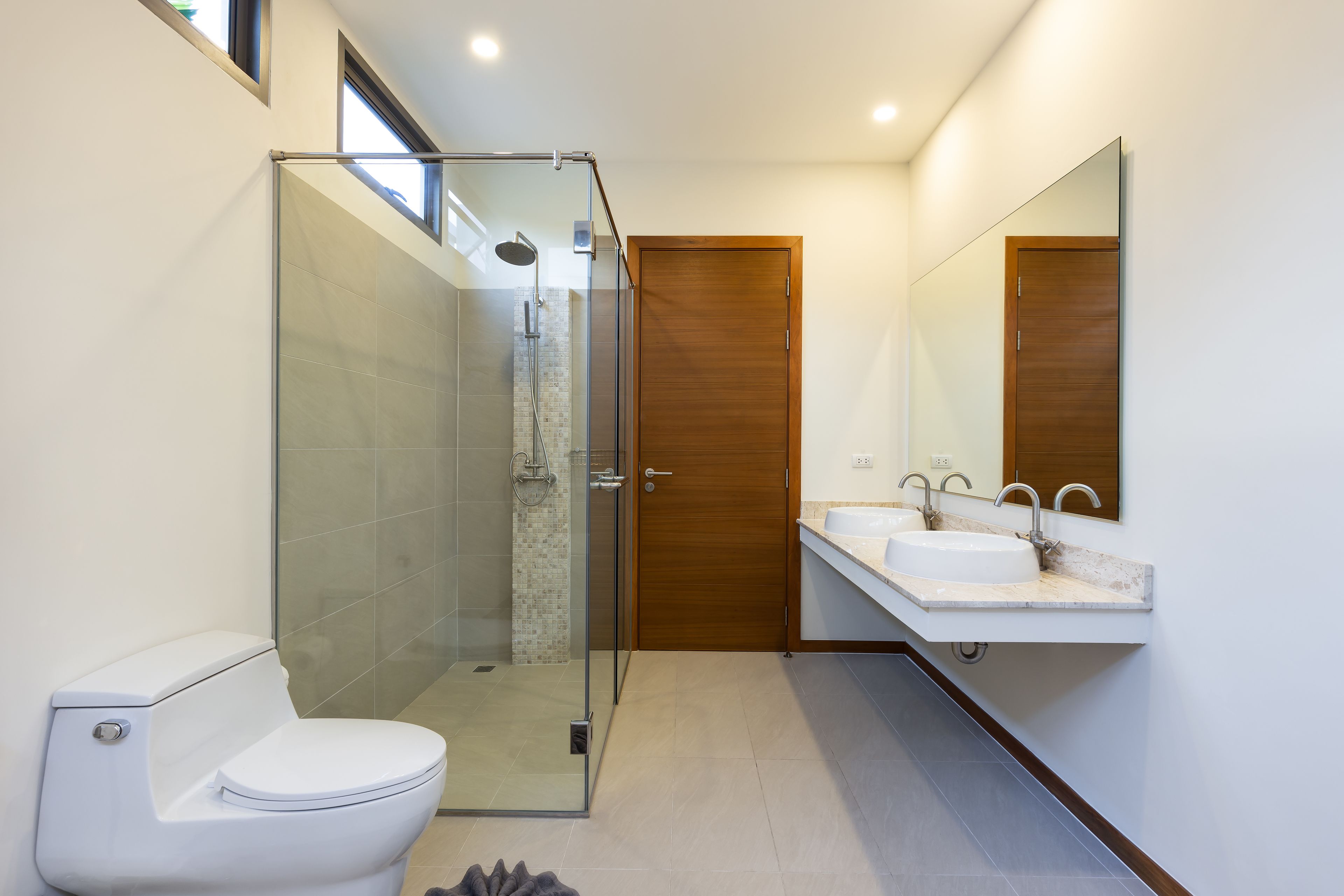 A modern bathroom with a glass-enclosed shower, a white toilet, and a double sink vanity.