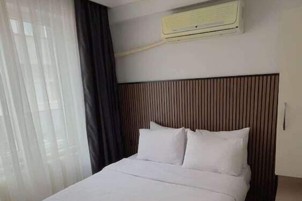 Une chambre d’hôtel avec un grand lit, un ventilateur de plafond, un appareil de climatisation et une fenêtre avec des rideaux.
