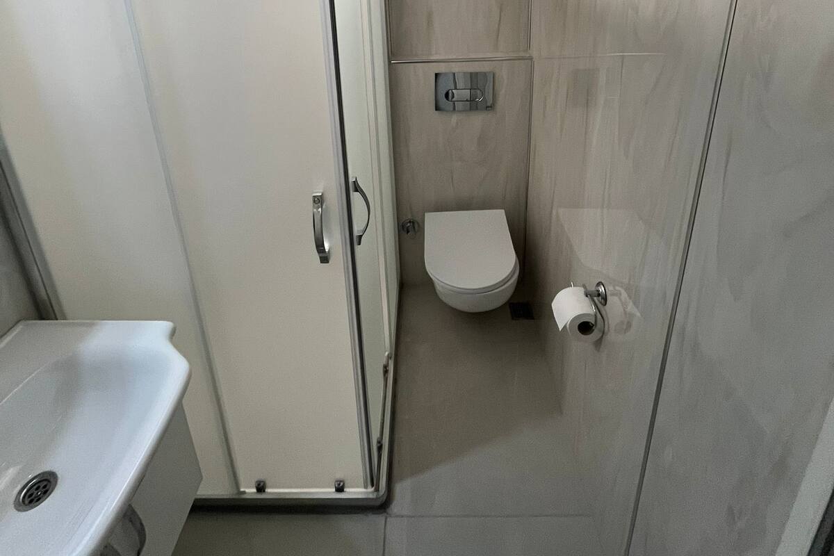 Une petite salle de bain moderne, équipée de toilettes, d’un lavabo et d’une douche.