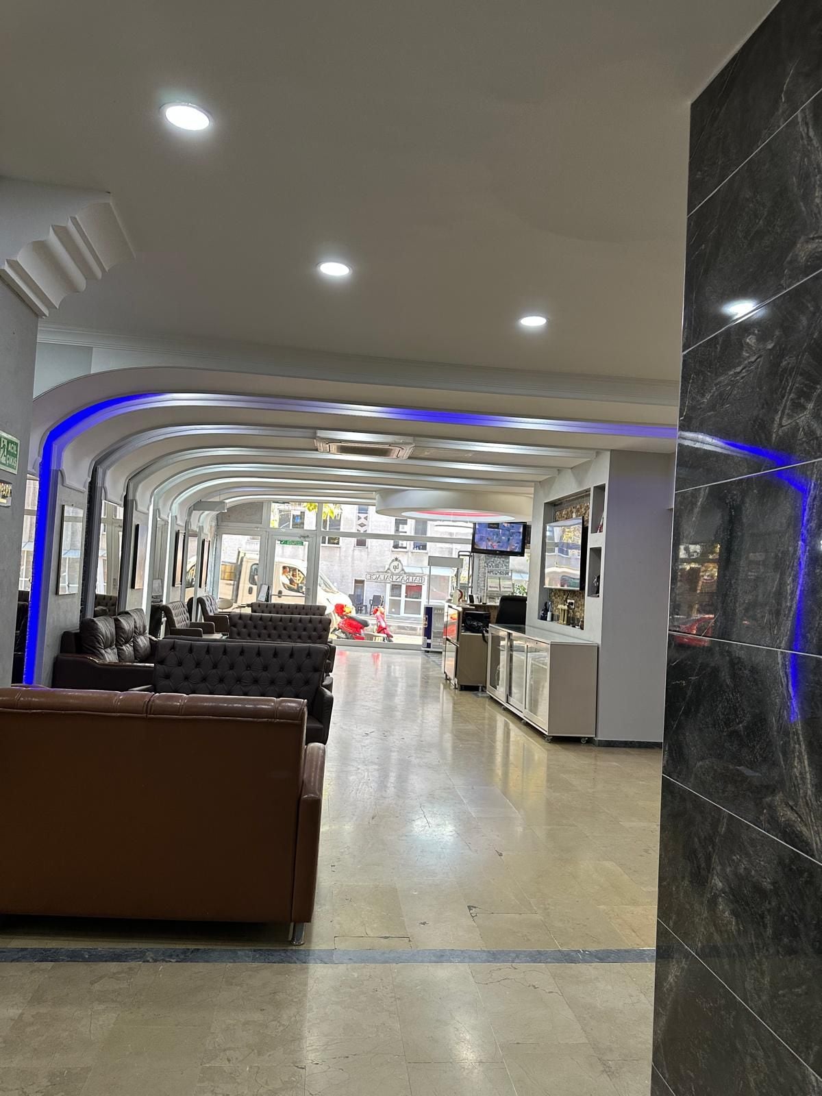 Un hall de hotel con recepción, zona de estar y vistas a la calle.