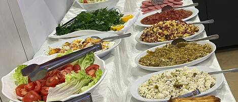 A buffet table with various dishes including salads, meats, and vegetables.