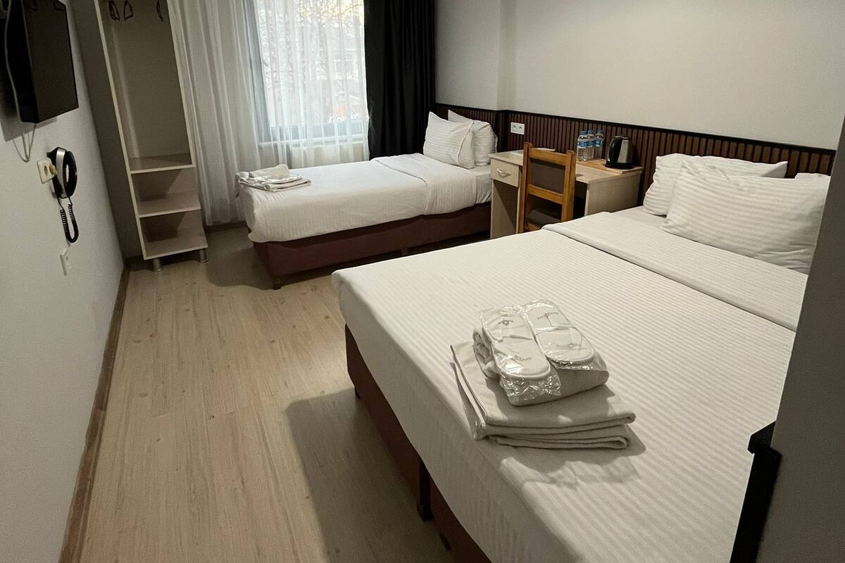 Une chambre d’hôtel avec deux lits, un bureau, une chaise, une télévision et une armoire.
