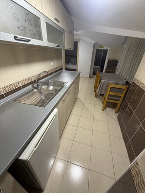 A compact kitchen with a stainless steel sink, a built-in oven, and a dining area with a table and chairs. - BALKAN PALACE EDIRNE (Edirne)