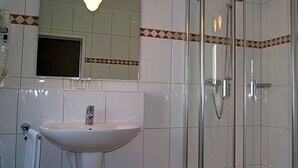 Un baño con lavamanos, espejo, ducha y paredes de azulejos.