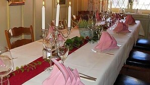 Una larga mesa de comedor cubierta con mantel blanco, servilletas rosas y candelabros.