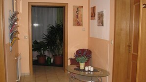 A hallway with a glass table, potted plants, and artwork on the walls. - Hotel Erzhausener Hof (Erzhausen)
