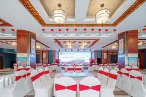 A conference room with rows of white chairs, a stage, and a large screen. - Phoenix International Hotel (Fenghuang Ancient Town Branch) (Fenghuang County)