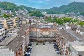 A traditional building with a courtyard, surrounded by other buildings, and a view of a hilly landscape. - Phoenix International Hotel (Fenghuang Ancient Town Branch) (Fenghuang County)