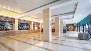A spacious lobby with marble flooring, high ceilings, and decorative wall murals. - Phoenix International Hotel (Fenghuang Ancient Town Branch) (Fenghuang County)