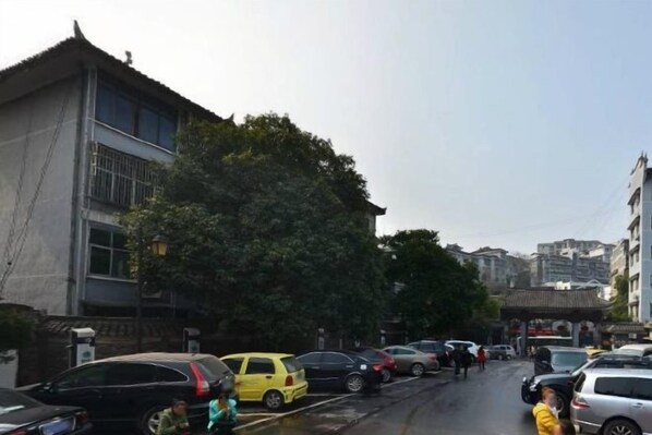 A street with parked cars and a building with a traditional architectural style. - Phoenix International Hotel (Fenghuang Ancient Town Branch) (Fenghuang County)