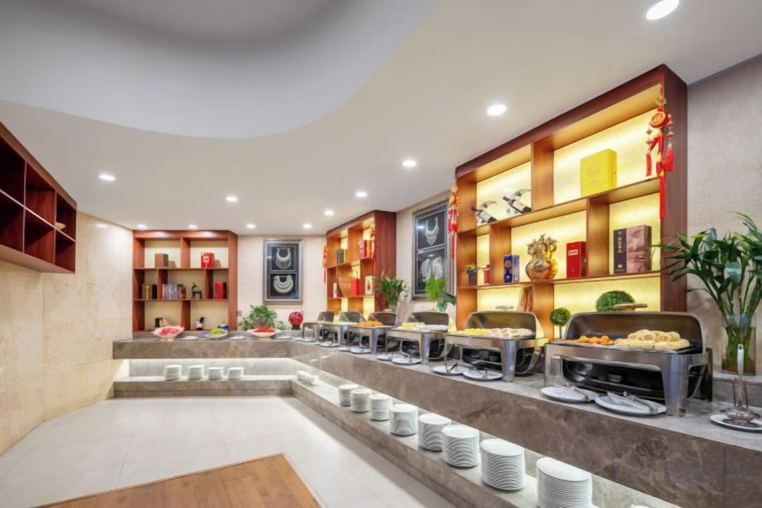 A hotel lobby with a reception desk, seating area, and a buffet with various food items.