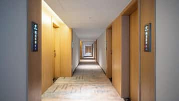 Corredor de hotel com portas de ambos os lados, cada uma identificada com um número de quarto.