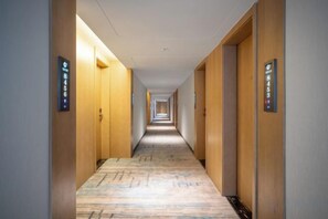 Een hotelgang met deuren aan beide kanten, elk voorzien van een kamernummer.