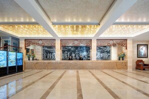 A spacious lobby with a marble floor, a reception desk, and a large wall mural. - Phoenix International Hotel (Fenghuang Ancient Town Branch) (Fenghuang County)
