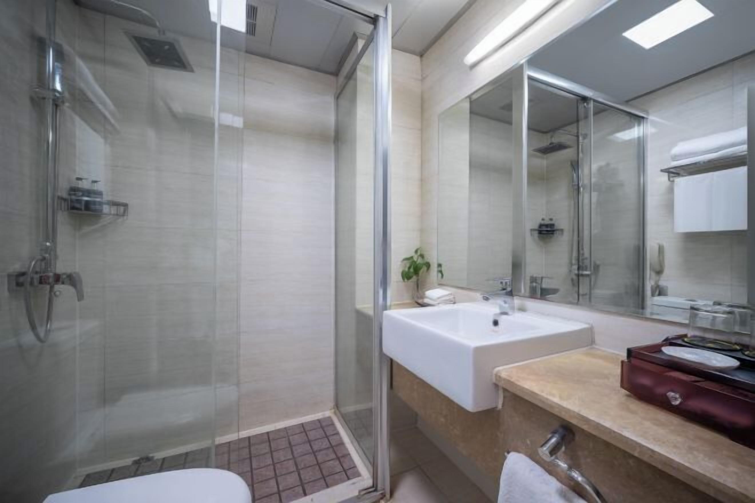 A modern bathroom with a glass-enclosed shower, a white sink, and a large mirror.