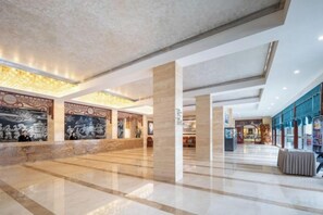 A spacious lobby with high ceilings, marble flooring, and decorative wall murals. - Phoenix International Hotel (Fenghuang Ancient Town Branch) (Fenghuang County)