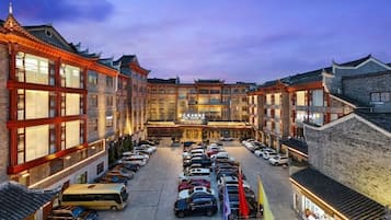 A hotel with a courtyard parking area, traditional architecture, and multiple floors.