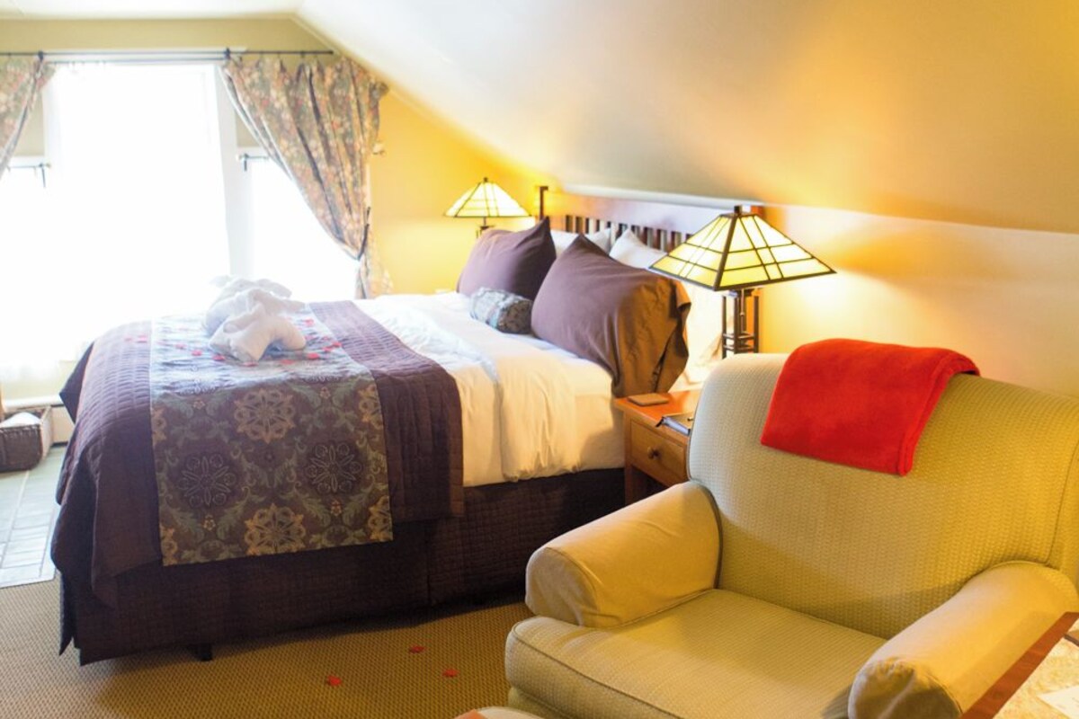 Ein Hotelzimmer mit Bett, Sofa, einem kleinen Tisch und einem Fenster mit Vorhängen.