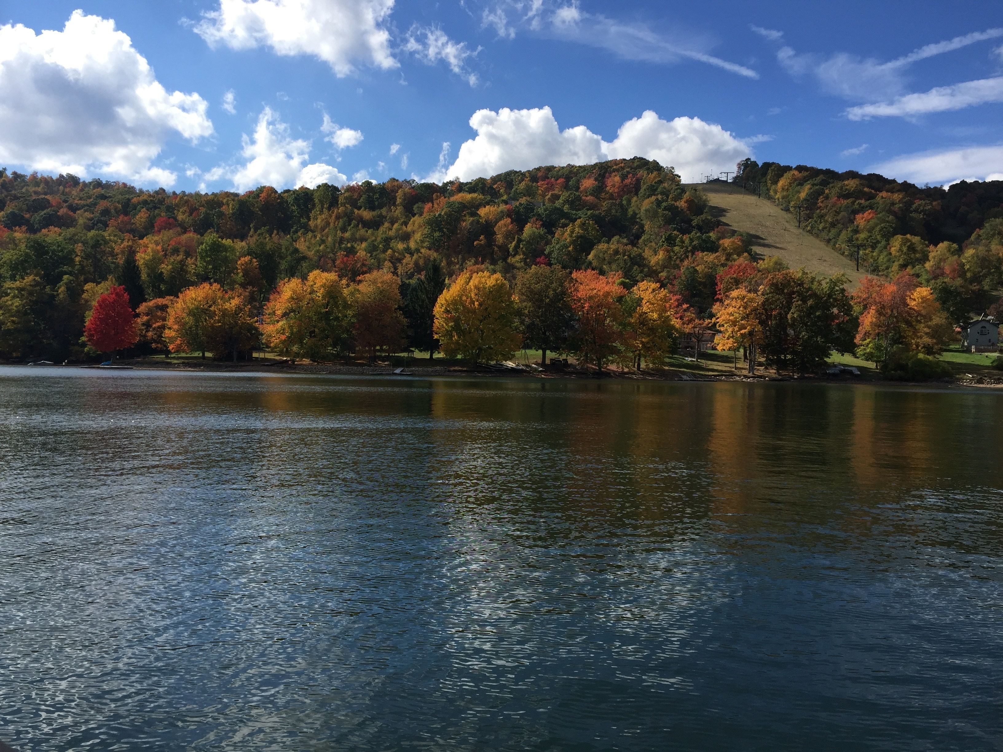 A lake with autumn-colored trees and a hill in the background.