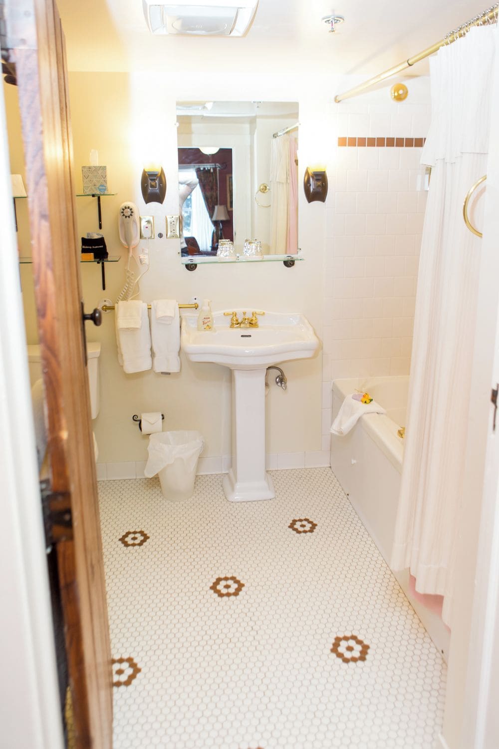 A bathroom with a white sink, toilet, and bathtub. There are towels hanging on the wall and a shower curtain.