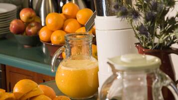 A breakfast buffet with oranges, a pitcher of orange juice, and a coffee maker.