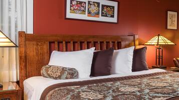 A neatly made bed with a patterned bedspread, a wooden headboard, and two bedside lamps.