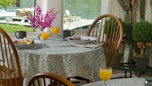 A dining area with a table set for two, a view of a lake, and a chair with a cushion. - Lake Pointe Inn (McHenry)