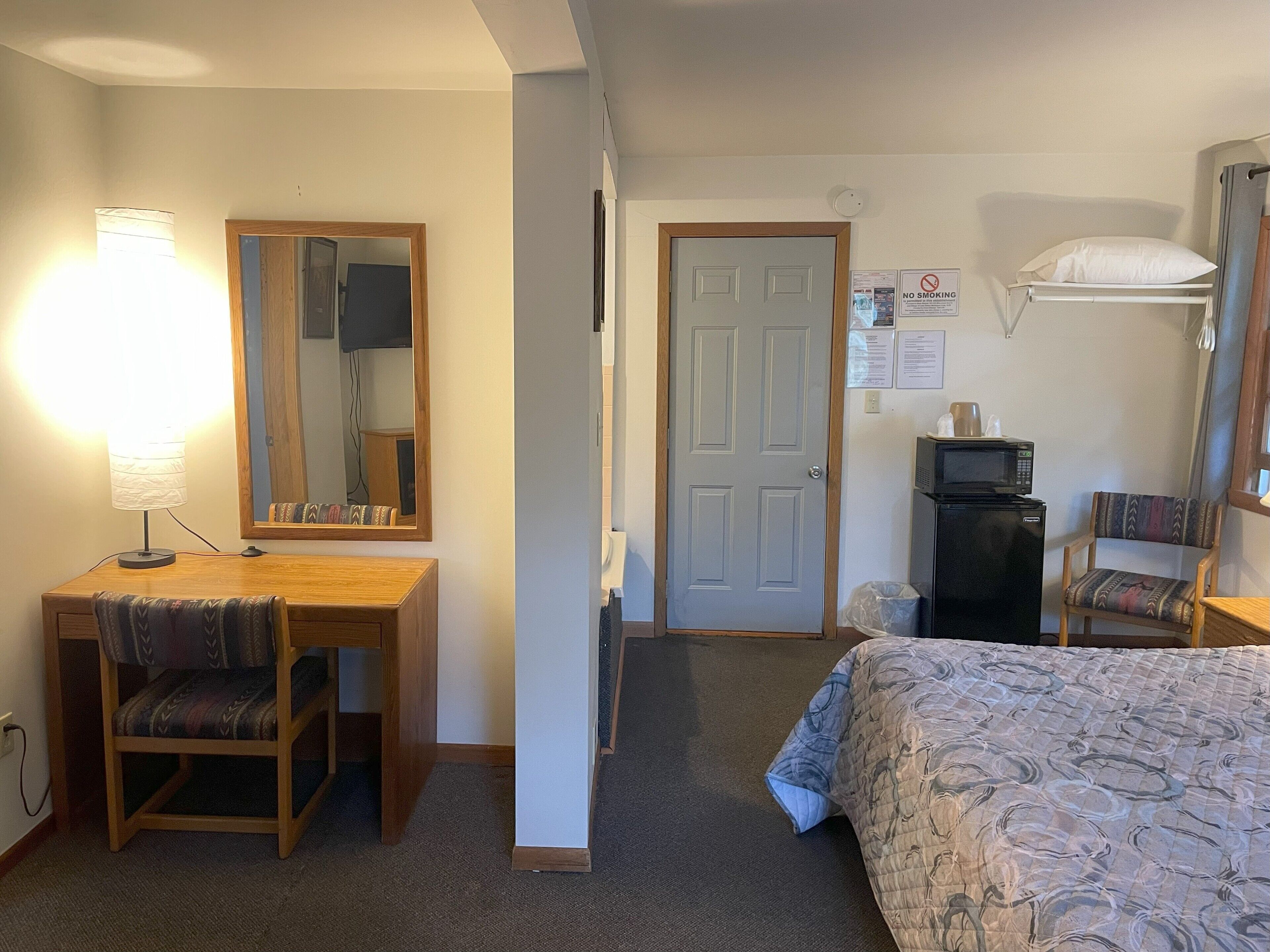 Ein Hotelzimmer mit Schreibtisch, Stuhl, Bett und einer Mikrowelle.