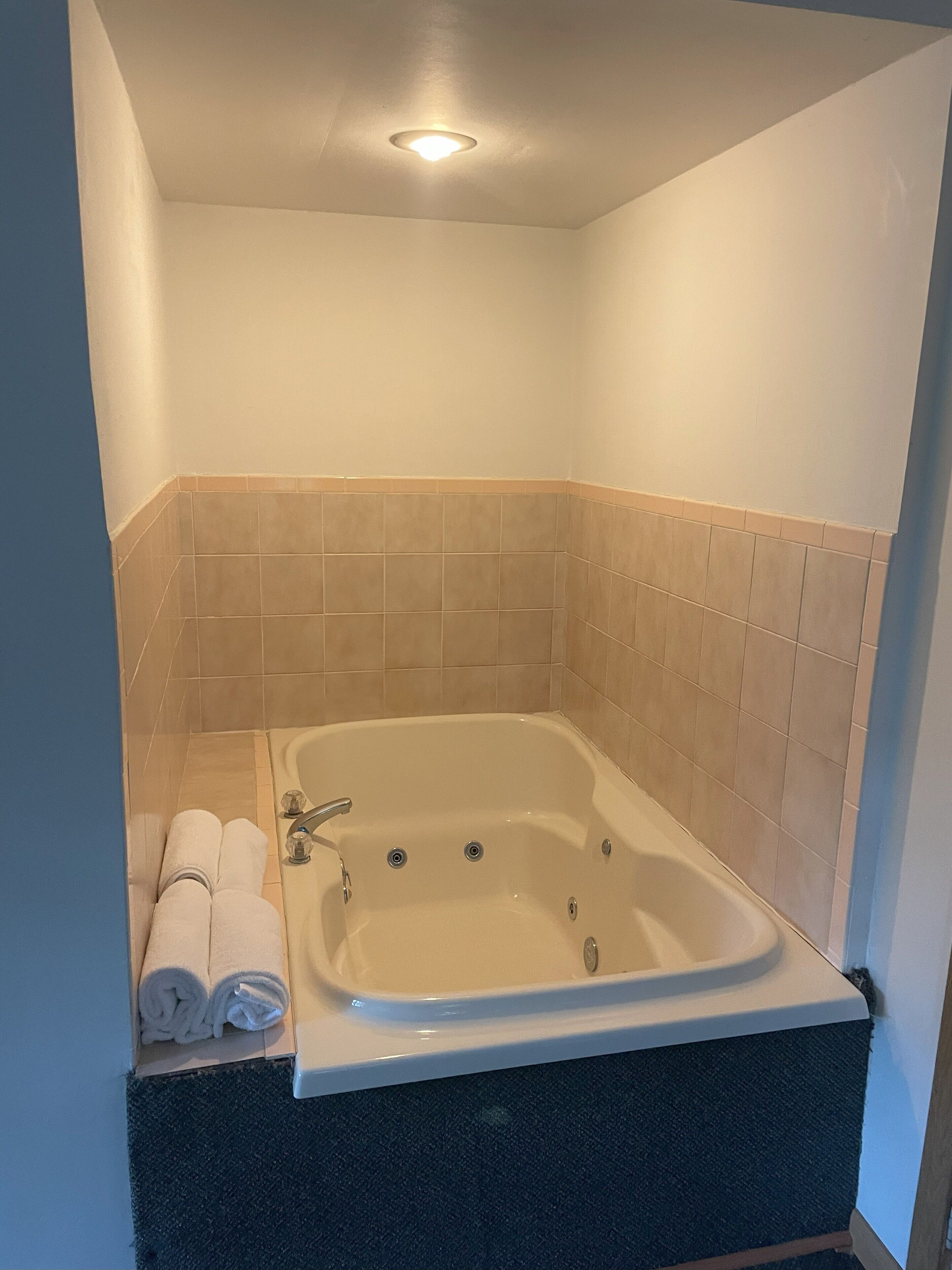 A small, modern bathroom with a freestanding bathtub, a towel rack with towels, and a ceiling light.