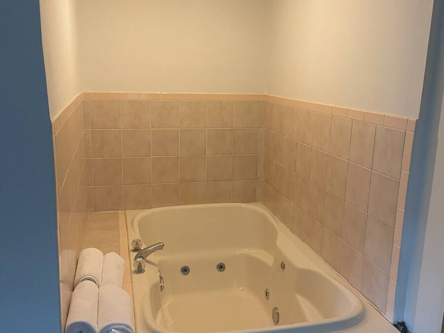 A small, modern bathroom with a freestanding bathtub, a towel rack with towels, and a ceiling light.