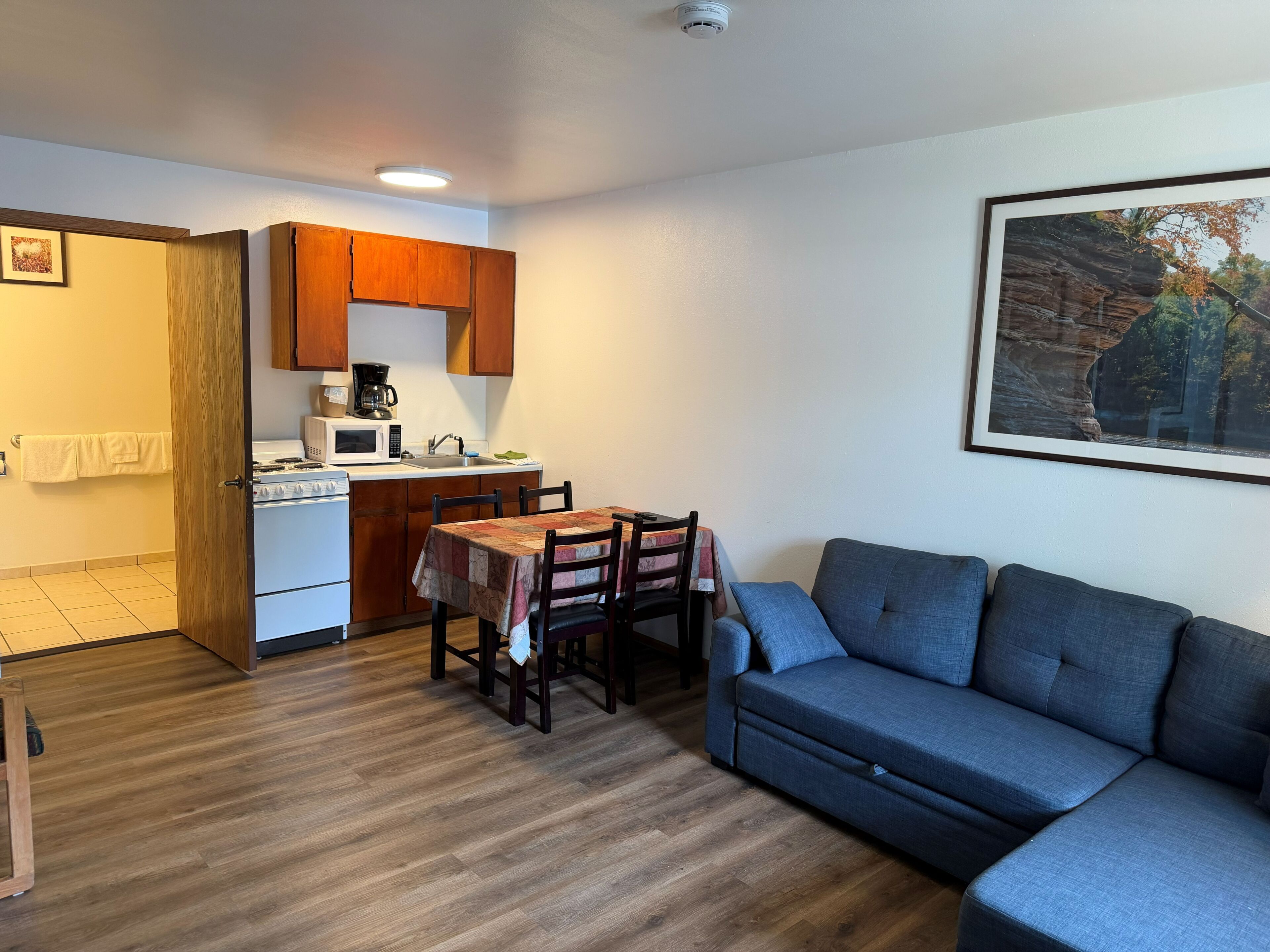 A compact living space with a kitchenette, a dining table, and a sofa.