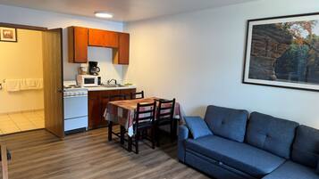 A compact living space with a kitchenette, a dining table, and a sofa.