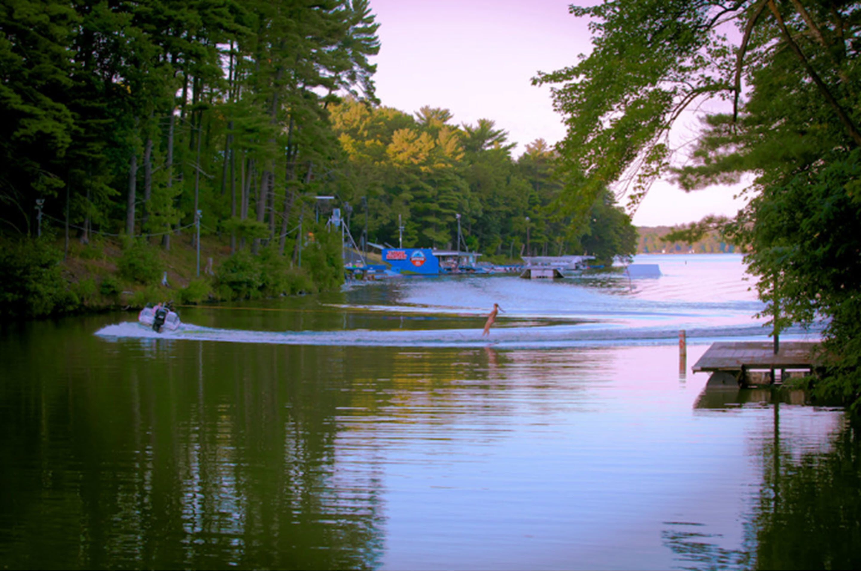 A calm lake with a dock and a boat.