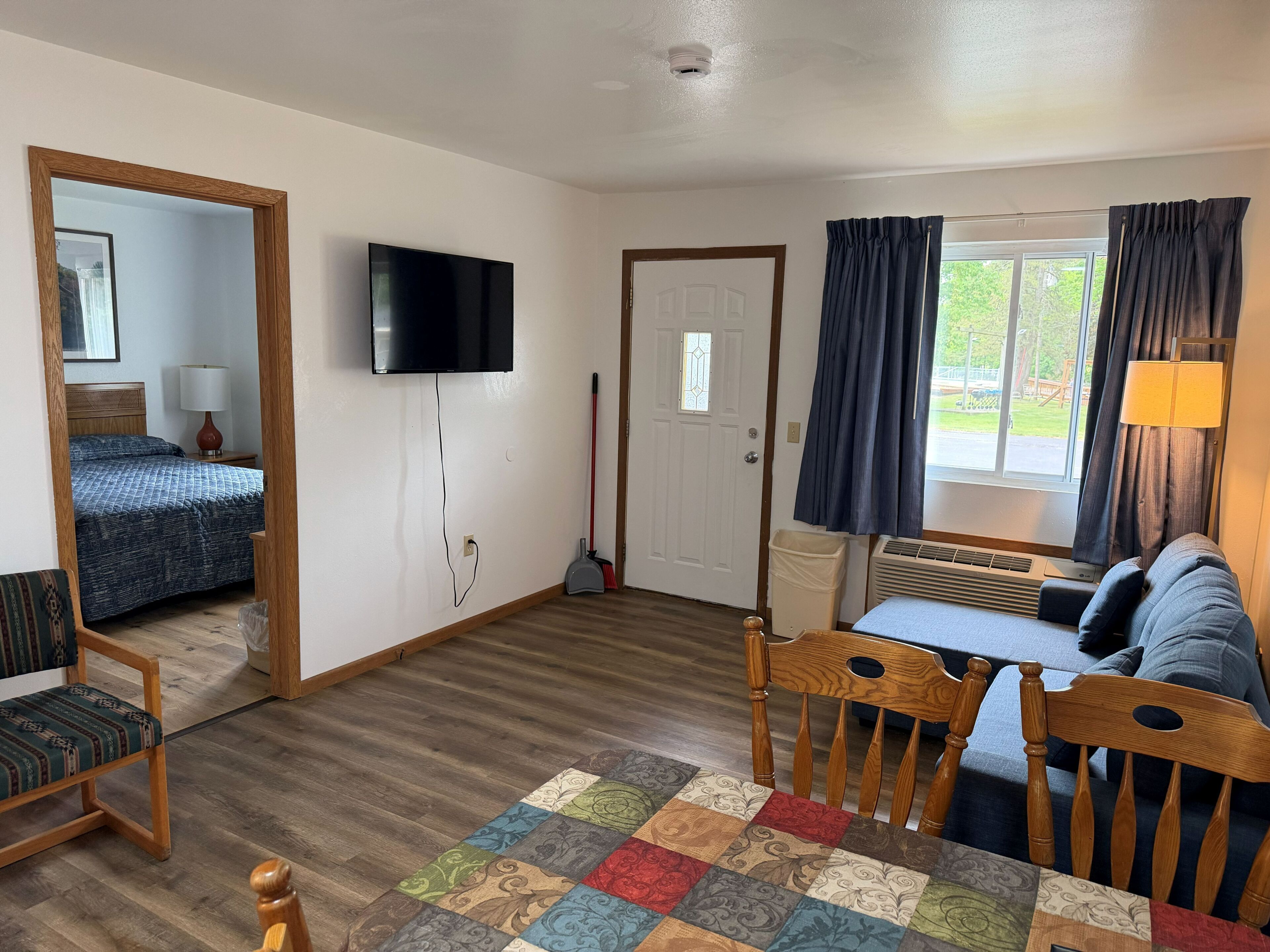 A room with a bed, a TV, a table, a chair, and a couch.