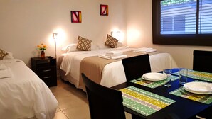 A hotel room with two beds, a dining table set with plates and glasses, and a window with blinds. - Umbral del Aconcagua (Mendoza)