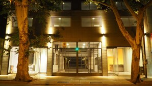 A building with a gated entrance, trees, and a well-lit facade at night. - Umbral del Aconcagua (Mendoza)