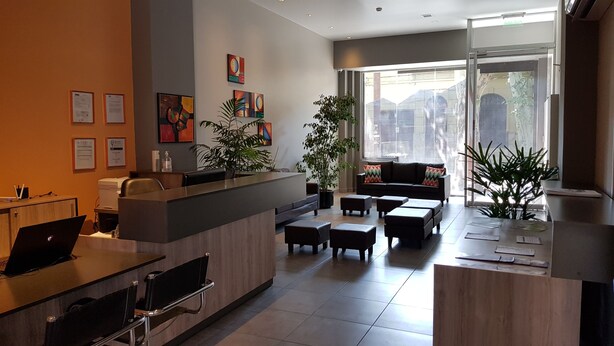 A modern reception area with a desk, computer, and seating area. There are plants and artwork on the walls. - Umbral del Aconcagua (Mendoza)