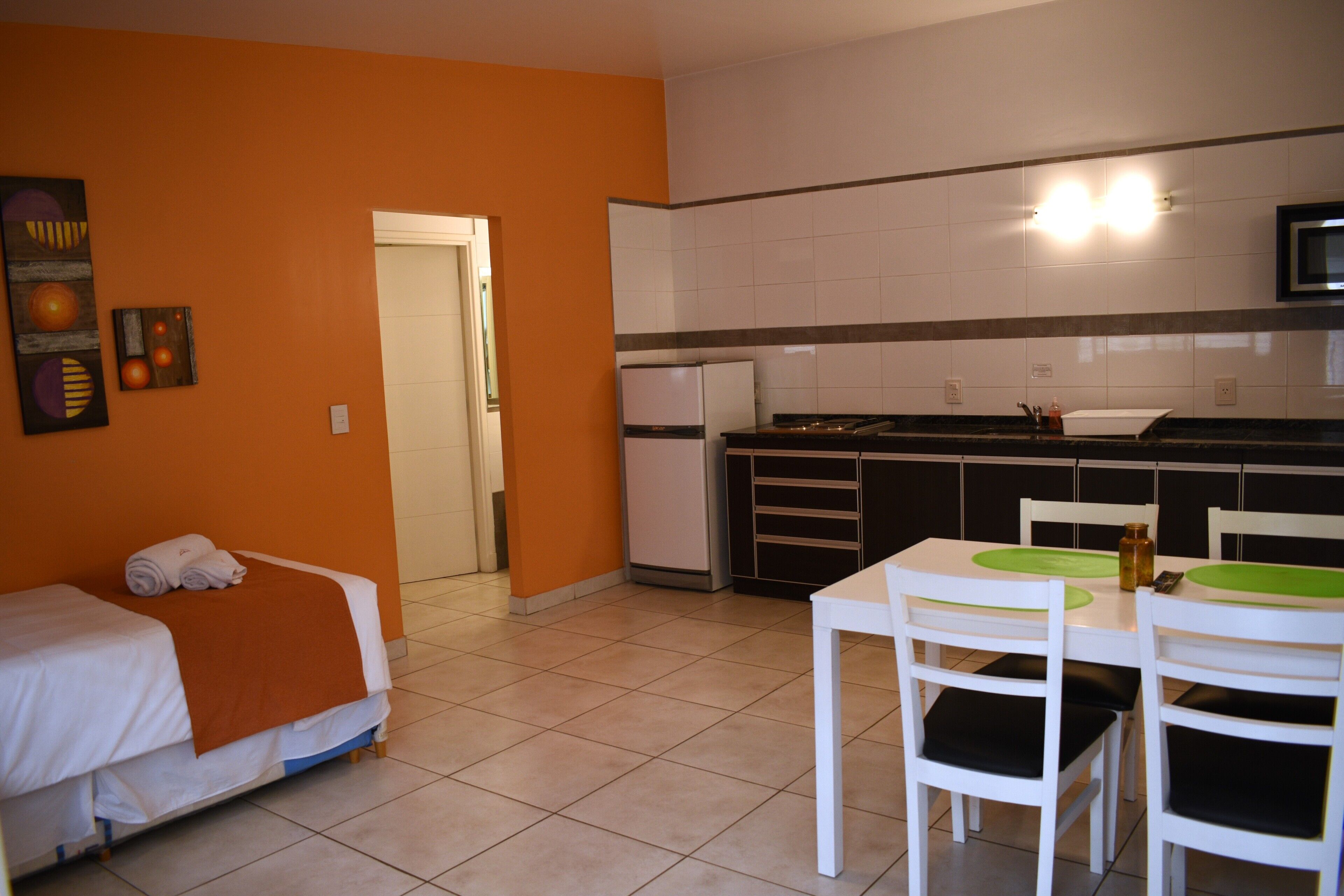 Una camera d'albergo compatta con un letto, un angolo cottura e un'area pranzo con sedie e tavolo.