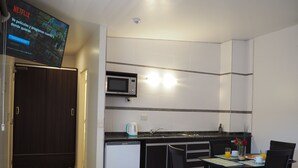 A compact kitchen with a microwave, a coffee maker, and a sink. There is a dining table with chairs and a small refrigerator. - Umbral del Aconcagua (Mendoza)
