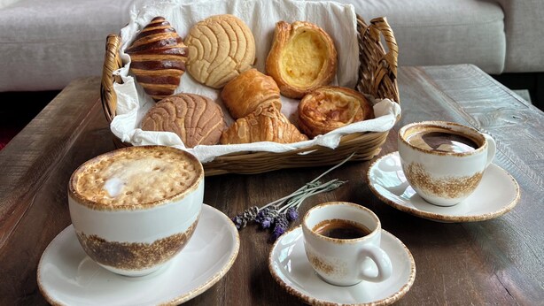 Un rincón acogedor con una cesta de mimbre llena de pasteles y tazas de café sobre una mesa de madera.