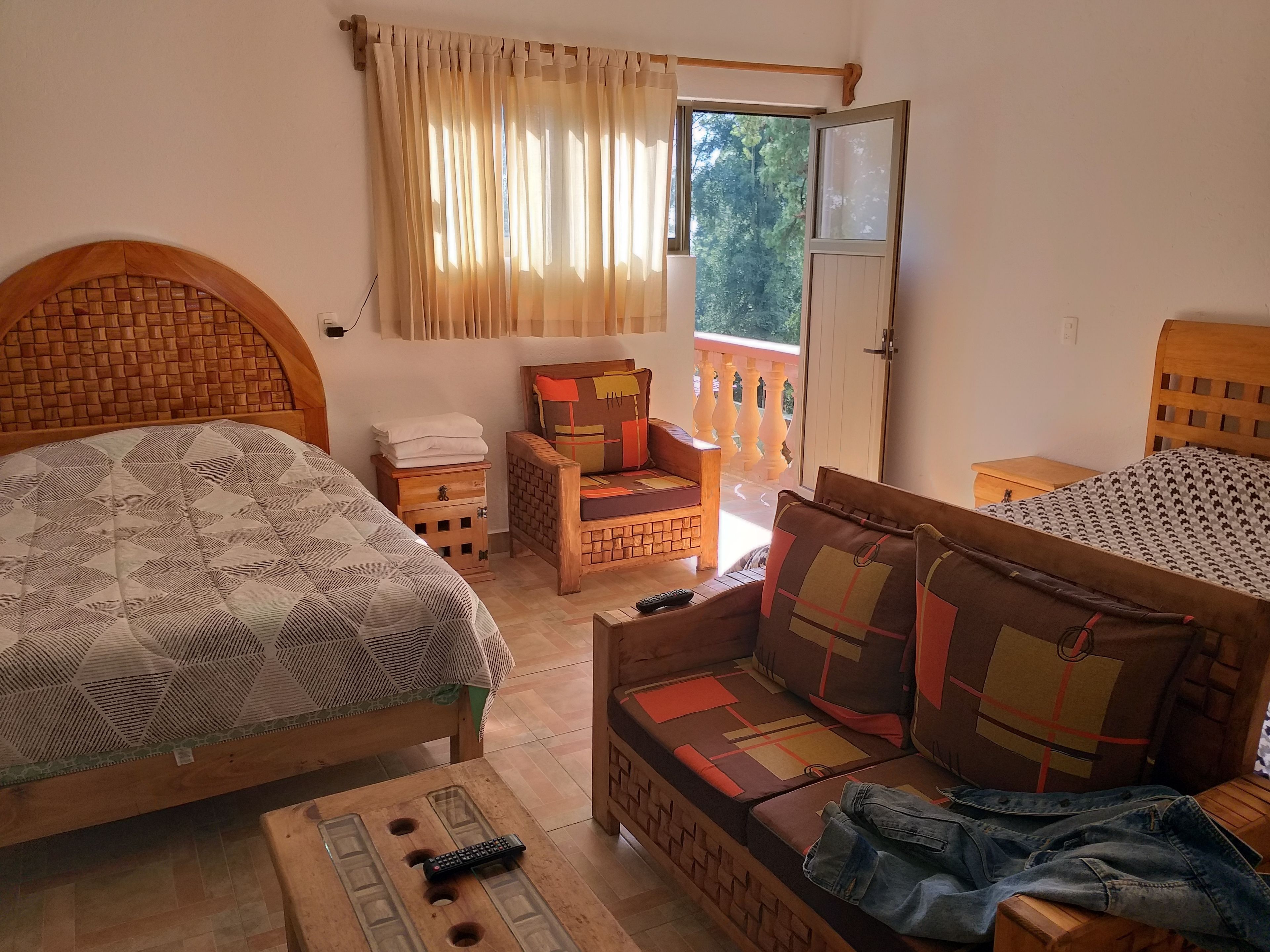 Un dormitorio con cama, sofá, mesita de noche y cabecera de madera.