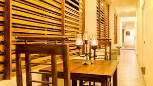 Ein Essbereich mit Holztisch und -stühlen, einem Kerzenleuchter und einer Wand aus Holzlamellen.