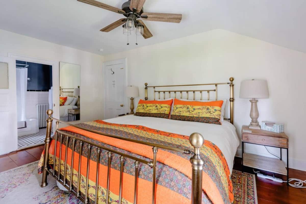 A bedroom with a bed, a ceiling fan, a bedside table with a lamp, and a nightstand.