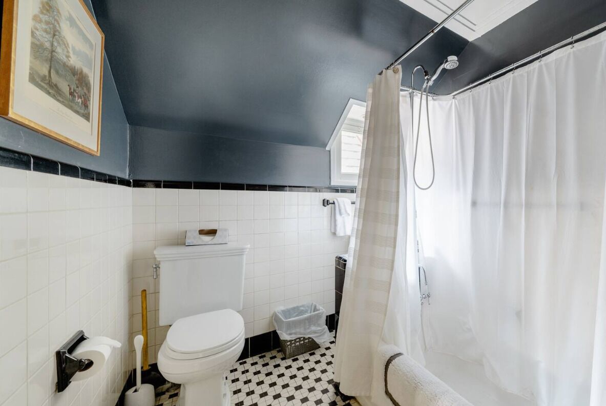 A bathroom with a white toilet, a shower curtain, and a tiled floor.