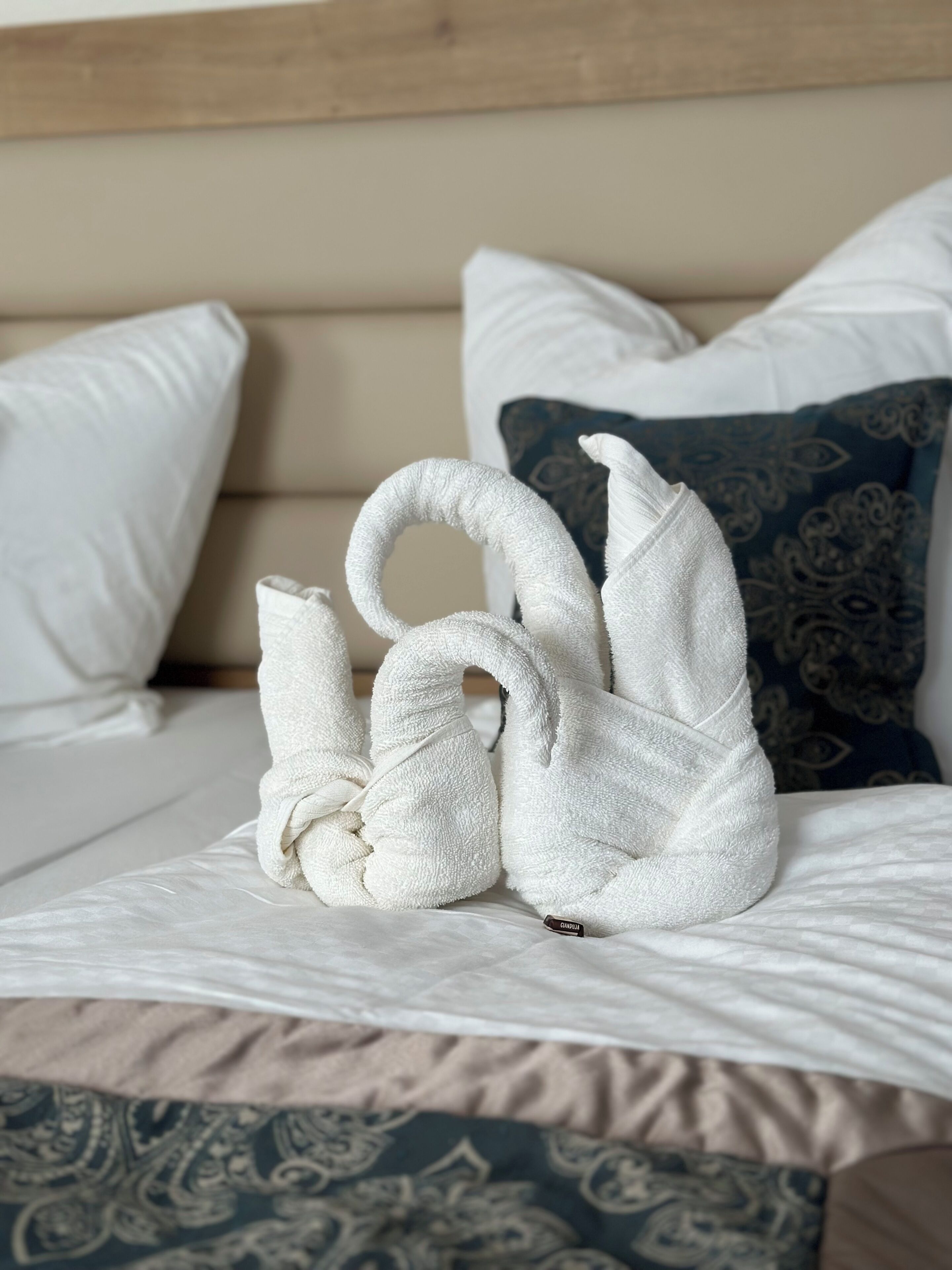 A bed with a white and patterned bedspread, a headboard, and decorative pillows.