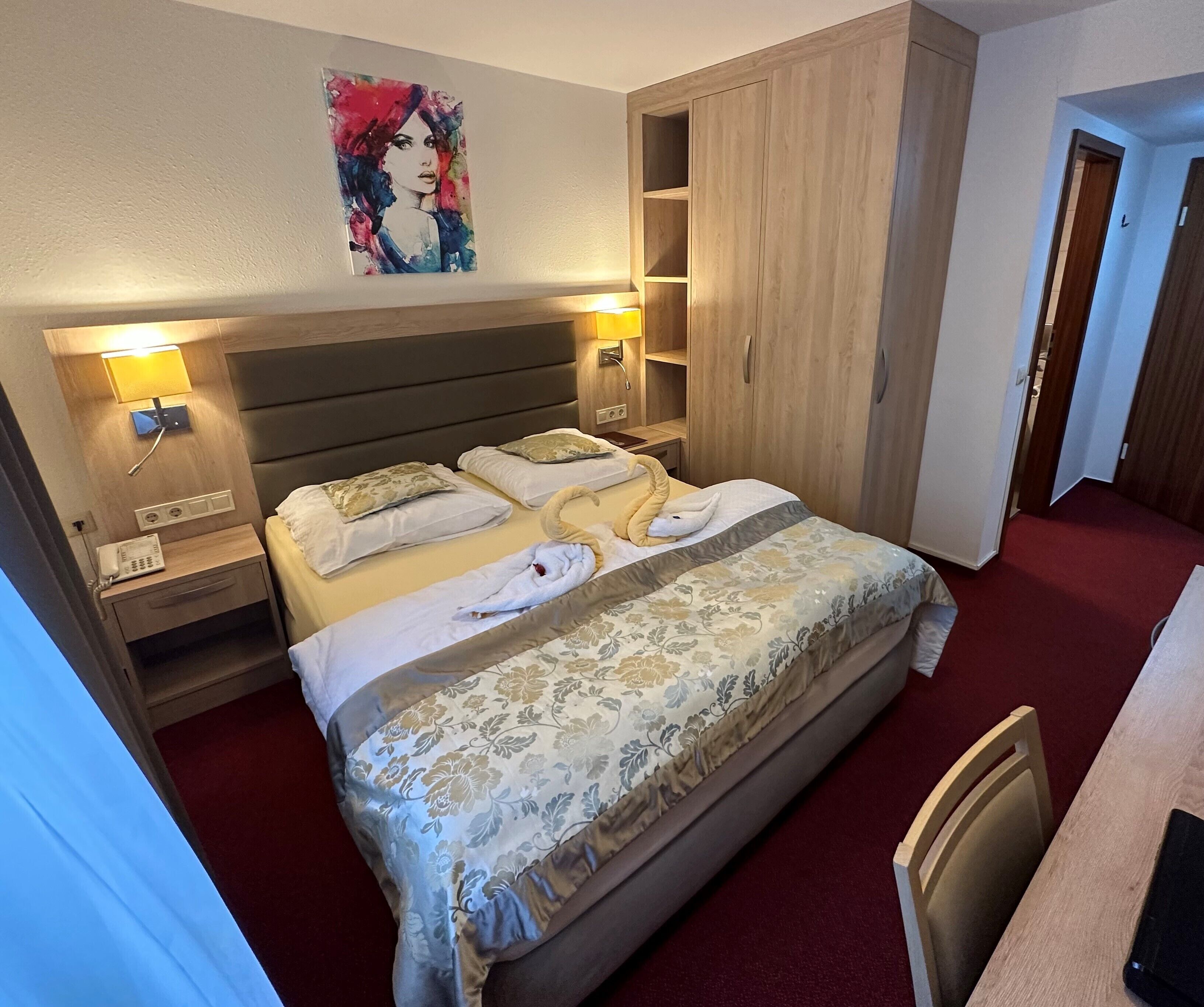 Une chambre d’hôtel avec un grand lit, des lampes de chevet, un téléphone et une armoire.